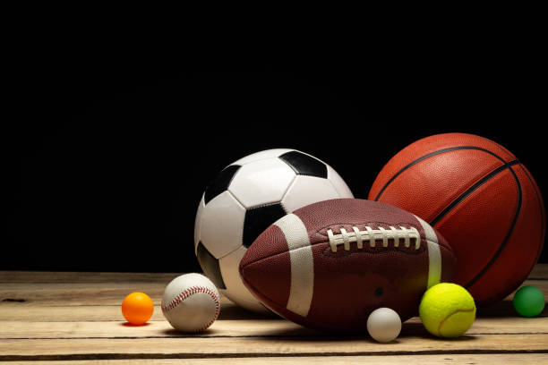 Set of various sport balls on wooden floor on black background close up